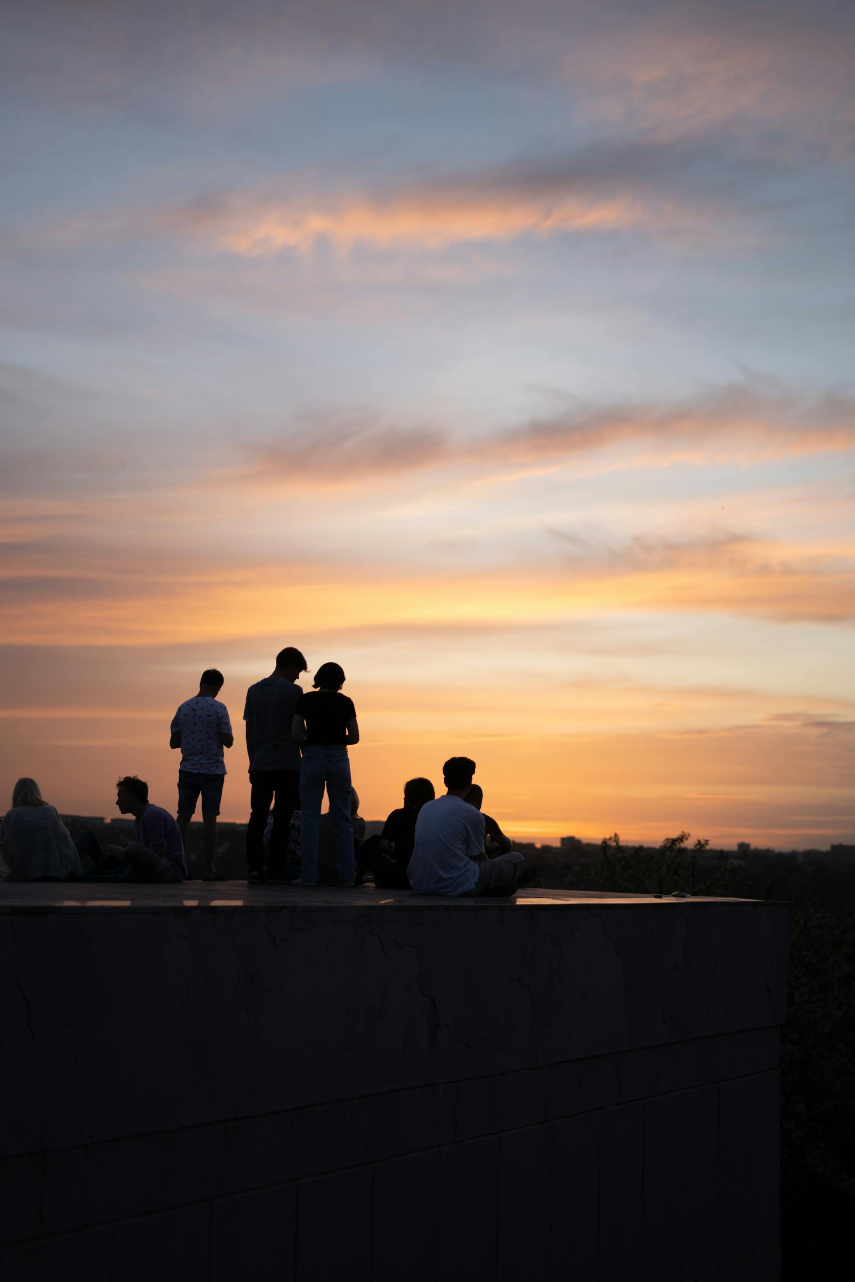 A group of people silhouetted against a beautiful sunset sky, creating a serene outdoor scene.