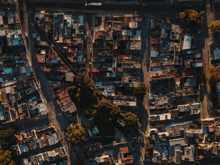 Drone shot capturing a dense residential area with streets and trees.